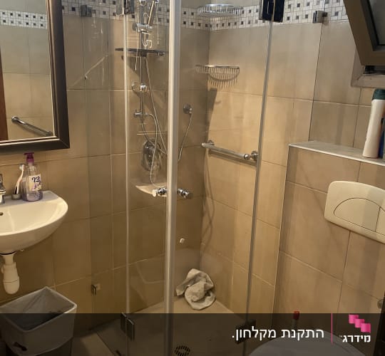 מקלחון זכוכית פינתי מותקן בחדר רחצה מרוצף